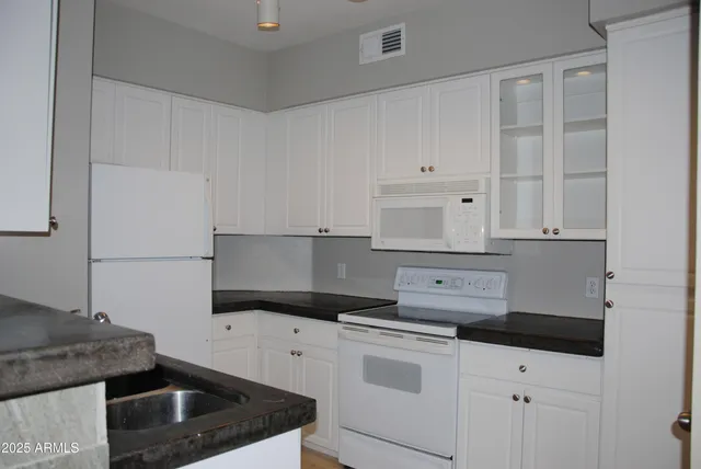 a kitchen with white cabinets and white appliances