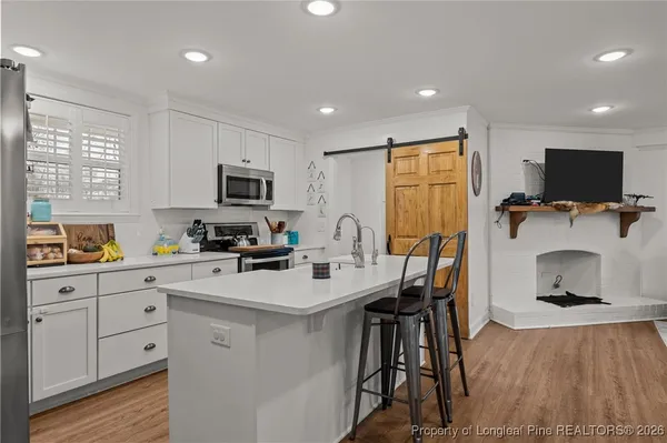 a kitchen with a sink microwave cabinets and wooden floor