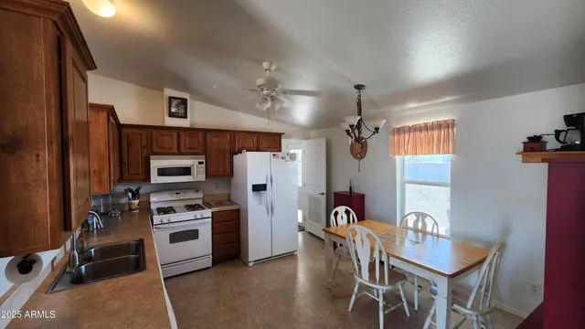 a kitchen with stainless steel appliances kitchen island granite countertop a refrigerator a stove top oven a sink dishwasher and a dining table with wooden floor