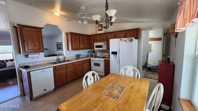 a kitchen with stainless steel appliances granite countertop a refrigerator a sink a stove a dining table and chairs with wooden floor