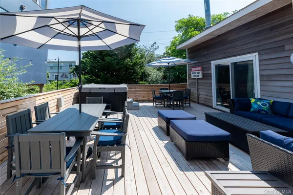 a view of a patio with table and chairs under an umbrella with a barbeque