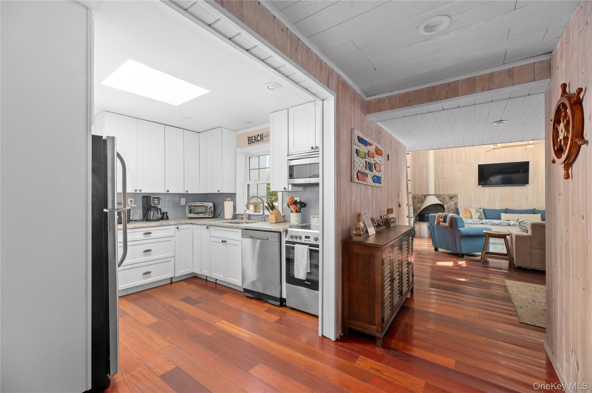 20 Seneca Walk Ocean Beach, NY 11770 - Photo 5 of 19 a kitchen with stainless steel appliances a stove top oven a refrigerator a dining table and chairs