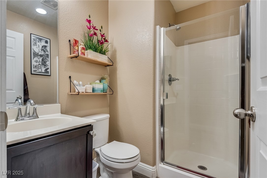 10519 Mann Street Las Vegas, NV 89141 - Photo 11 of 48 Full bathroom featuring a stall shower, toilet, a textured wall, and vanity