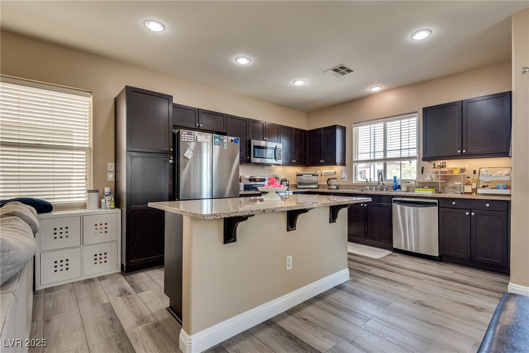10519 Mann Street Las Vegas, NV 89141 - Photo 17 of 48 Kitchen featuring stainless steel appliances, a breakfast bar, light wood style finished floors, grantie countertops, and recessed lighting