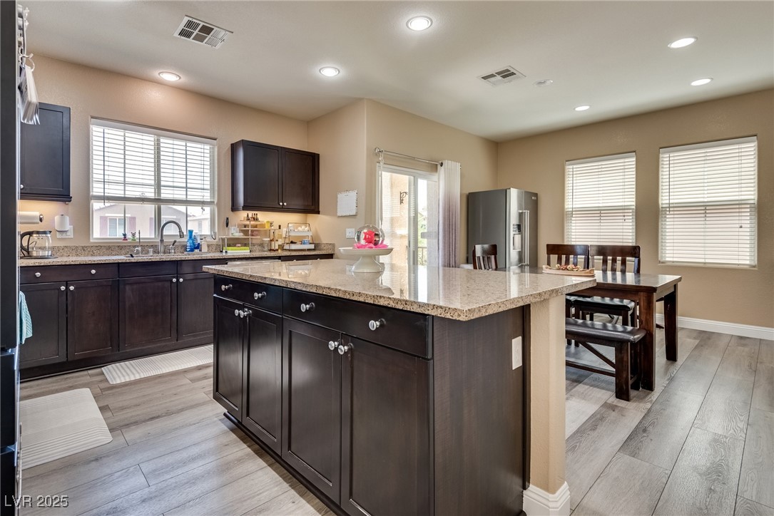 10519 Mann Street Las Vegas, NV 89141 - Photo 20 of 48 Kitchen with stainless steel refrigerator with ice dispenser, a kitchen island, light wood-style flooring, light stone counters, and recessed lighting