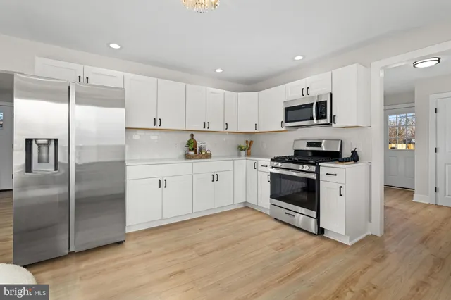 a kitchen with cabinets stainless steel appliances and wooden floor