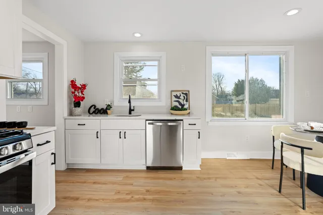 a kitchen with white cabinets and wooden floor