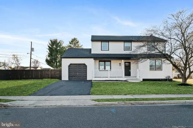 a front view of a house with a garden and trees