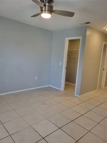 a view of an empty room and chandelier fan