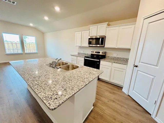 a kitchen with stainless steel appliances granite countertop a sink stove microwave and refrigerator