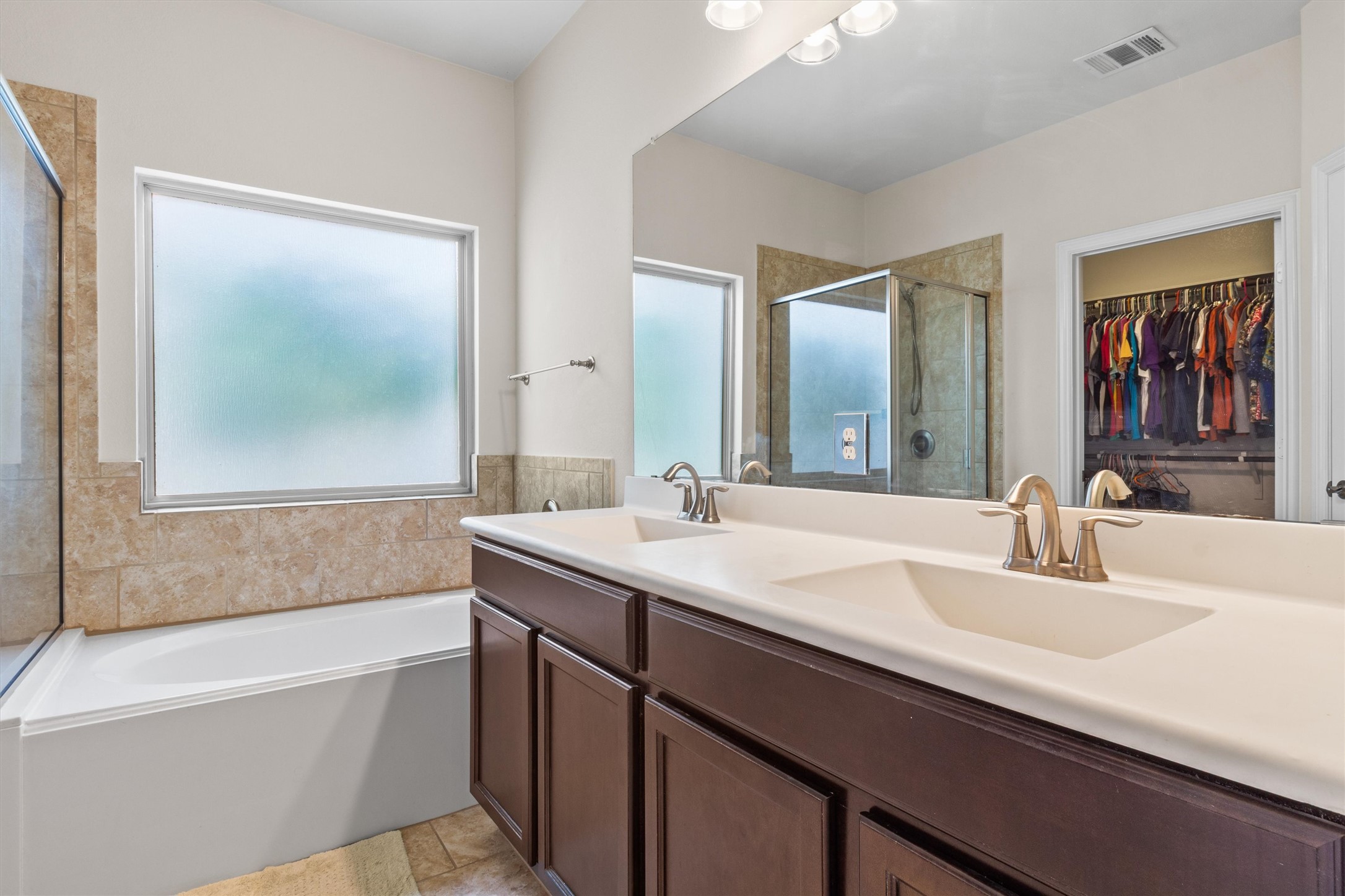 10413 Crescendo Lane Austin, TX 78747 - Photo 17 of 32 A tranquil primary bathroom features a generous soaking tub, separate glass-enclosed shower, and a double vanity.