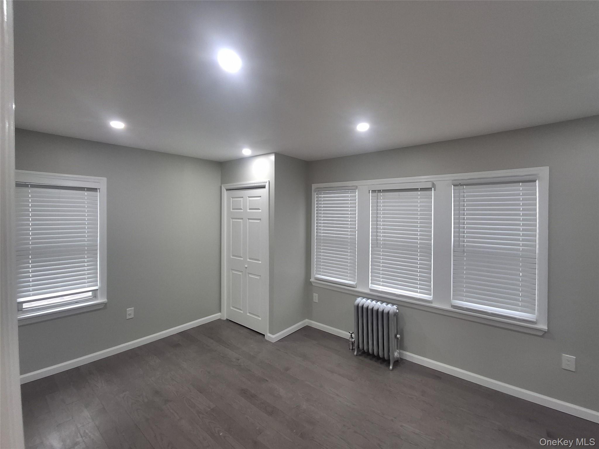 194-14 115th Road, Unit 2 Queens, NY 11412 - Photo 7 of 11 Spare room with radiator, dark wood-type flooring, and recessed lighting