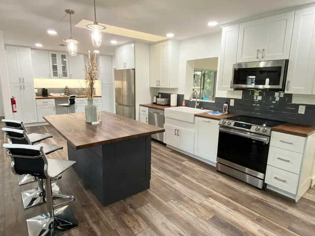 a kitchen with stainless steel appliances kitchen island granite countertop a stove a sink dishwasher and a refrigerator with wooden floor