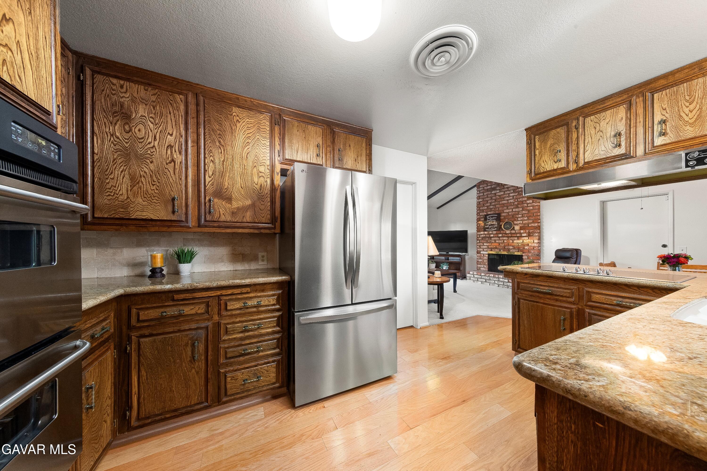 43755 Sentry Lane Lancaster, CA 93536 - Photo 13 of 36 a kitchen with stainless steel appliances granite countertop a refrigerator a sink dishwasher a stove and white countertops with wooden floor