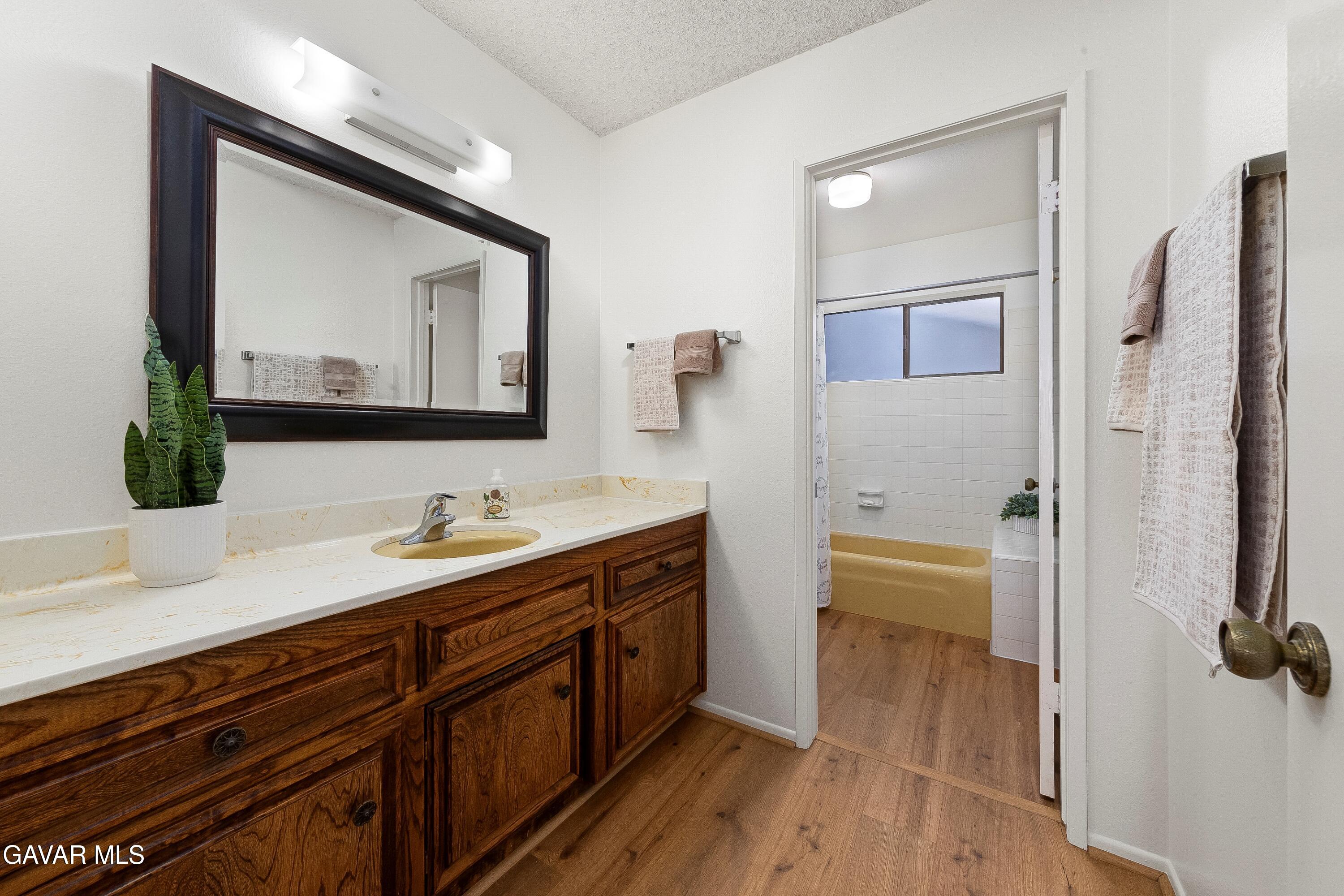 43755 Sentry Lane Lancaster, CA 93536 - Photo 21 of 36 a bathroom with a double vanity sink a mirror and a bathtub