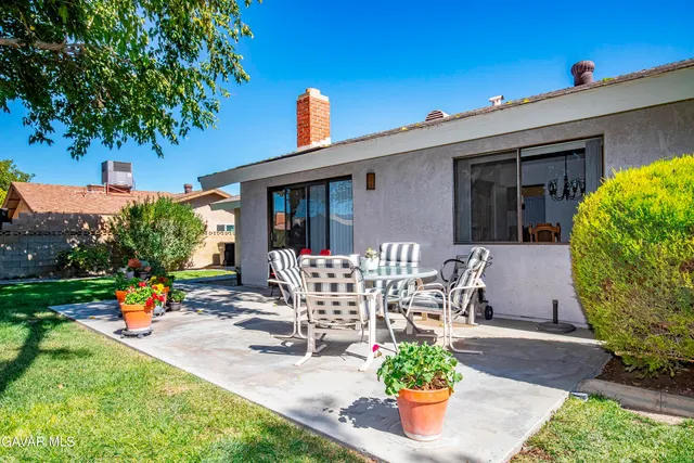 a view of a patio with table and chairs potted plants and a large tree