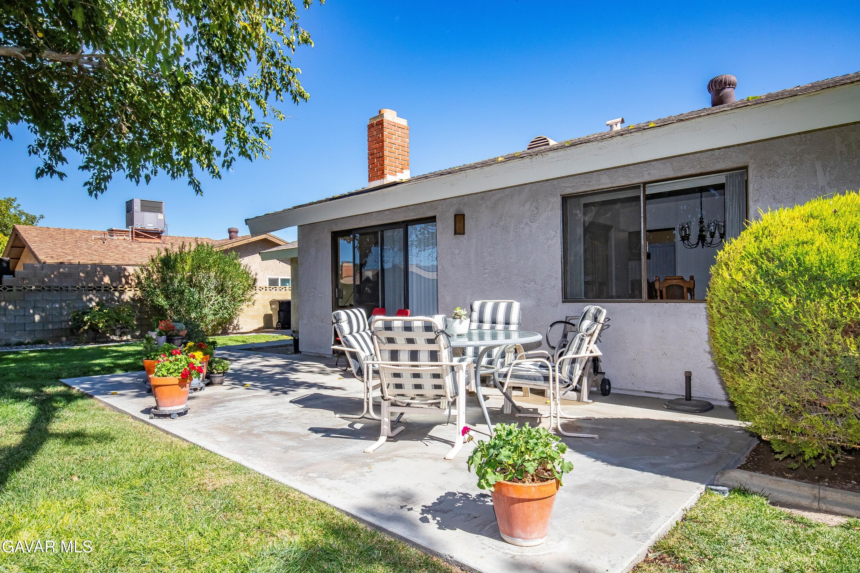 43755 Sentry Lane Lancaster, CA 93536 - Photo 28 of 36 a view of a patio with table and chairs potted plants and a large tree