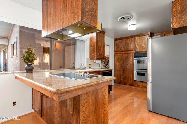 a kitchen with a sink a counter top space stainless steel appliances and cabinets