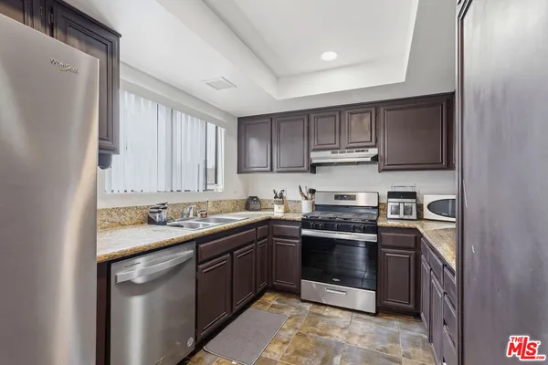 a kitchen with granite countertop a stove top oven microwave and cabinets