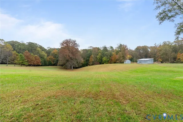 a view of a white house with a yard and large tree