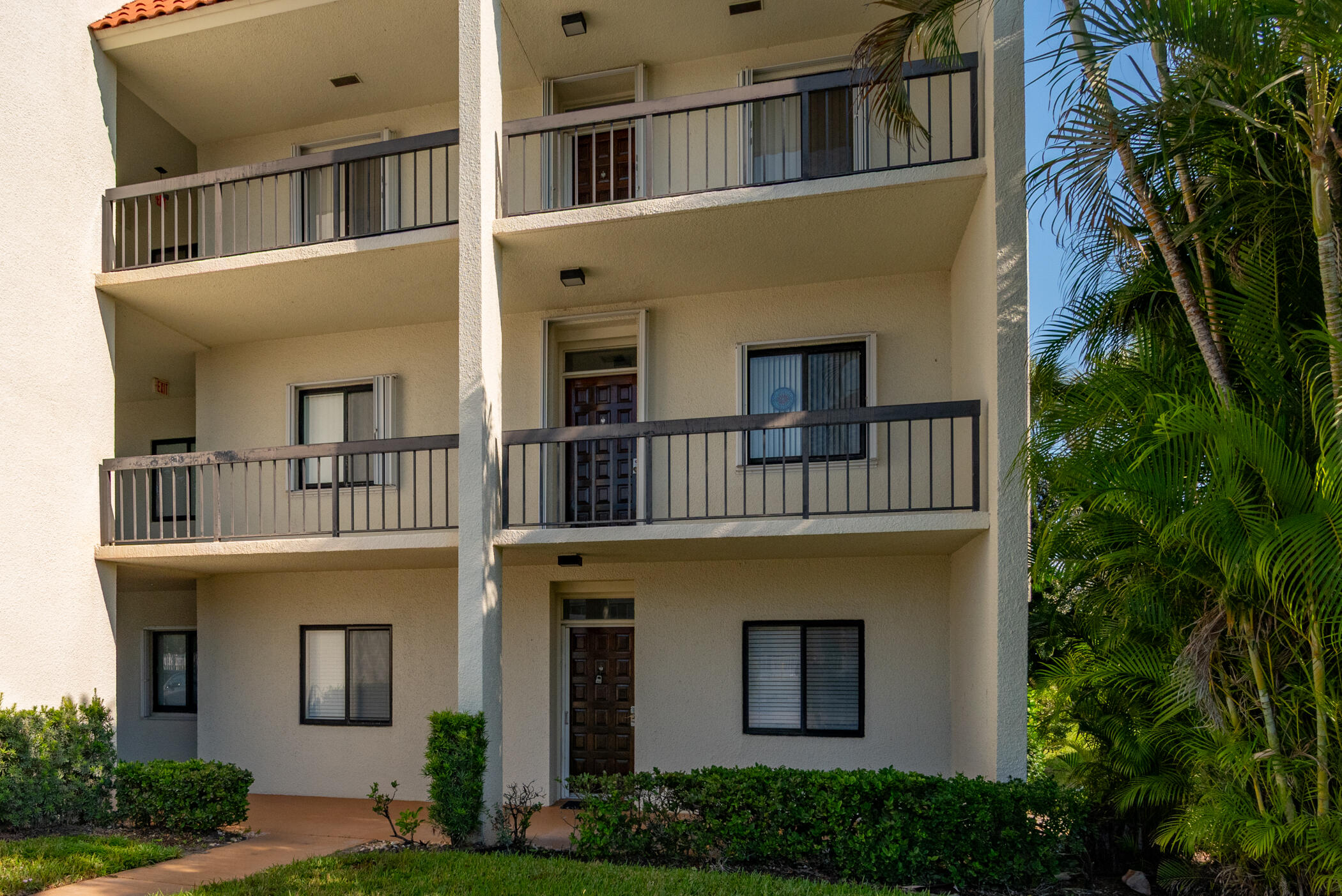2550 Presidential Way, Unit 107 West Palm Beach, FL 33401 - Photo 26 of 28 a front view of a house with a yard and trees