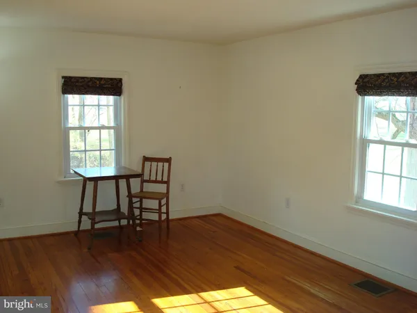a view of a workspace room with wooden floor and a window