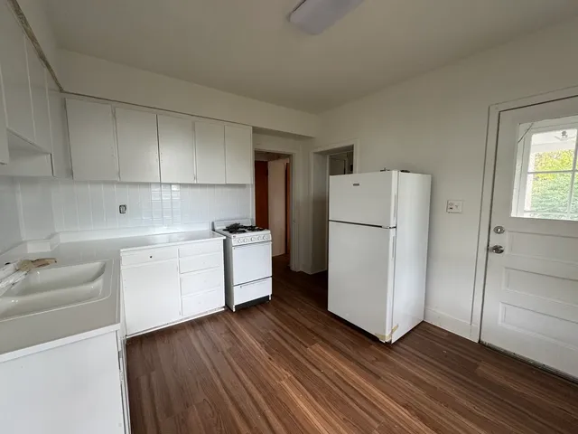 a kitchen with a refrigerator a sink and dishwasher with white cabinets