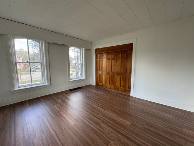 an empty room with wooden floor and windows