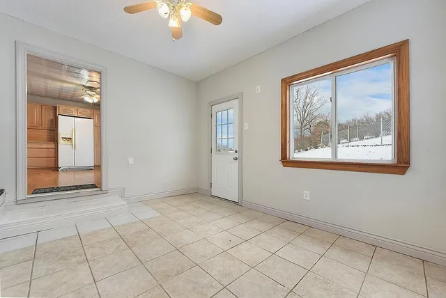 a view of an empty room with window and chandelier fan