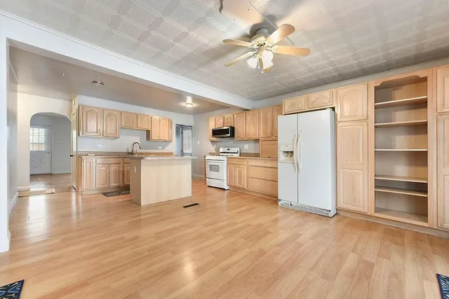 a room with stainless steel appliances kitchen island wooden floors and white cabinets