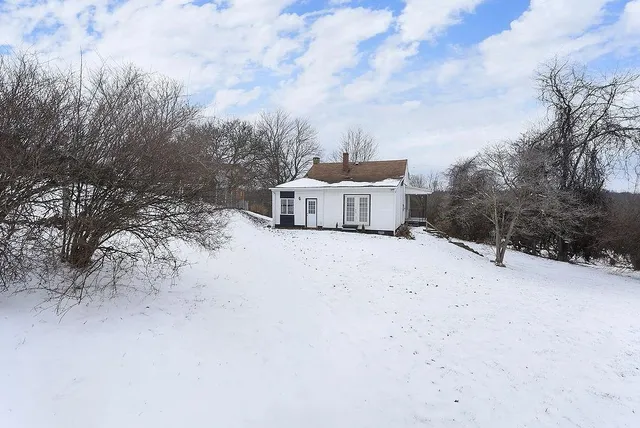 a white house that has a lots of snow on the side of the road