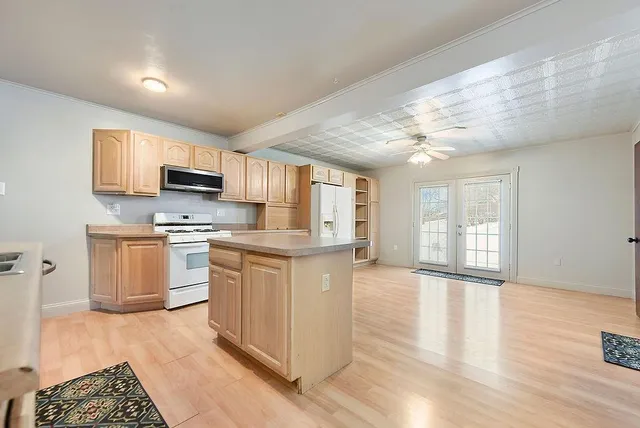 a kitchen with kitchen island granite countertop a stove top oven a sink a counter space and cabinets