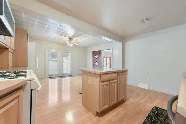a hall with kitchen island white cabinets and wooden floor