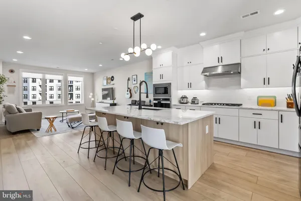 a kitchen with stainless steel appliances a kitchen island a stove a table and chairs in it