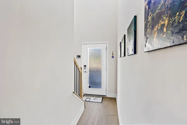 a view of a hallway with wooden floor and a bathroom