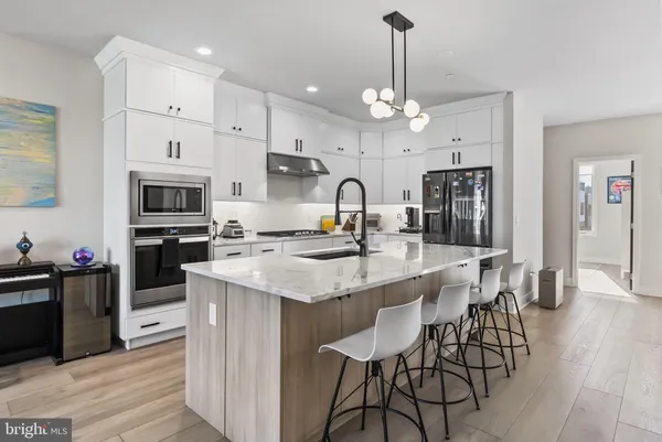 a kitchen with stainless steel appliances kitchen island granite countertop a table chairs and a refrigerator