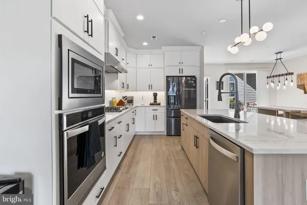 a large kitchen with stainless steel appliances granite countertop a sink a stove and oven