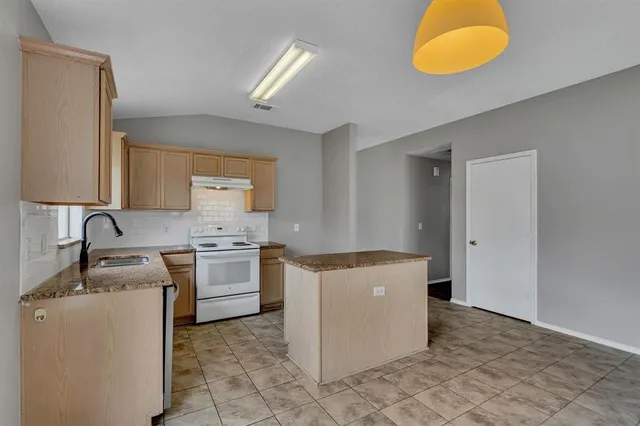 a kitchen with granite countertop a sink stove and cabinets