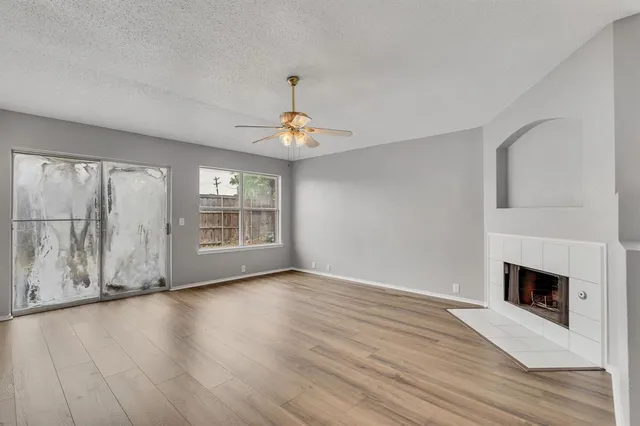 a view of an empty room with window and chandelier fan