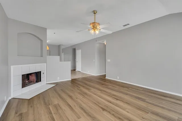 a view of empty room with wooden floor and fireplace