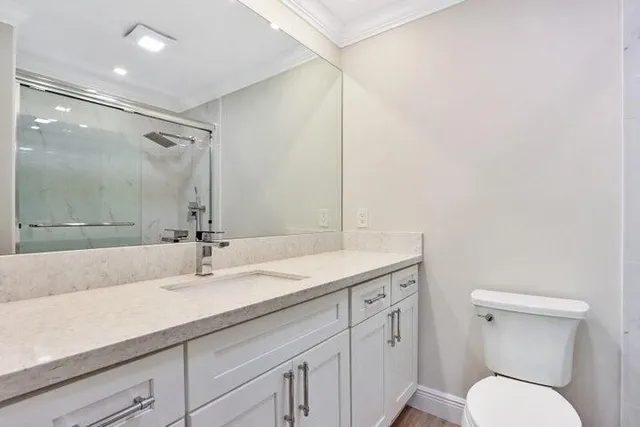 a bathroom with a granite countertop sink a toilet and a mirror