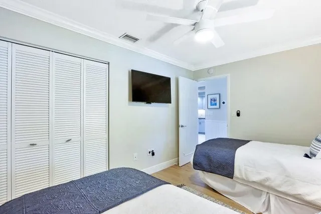 a bedroom with a large bed a flat tv screen and a ceiling fan