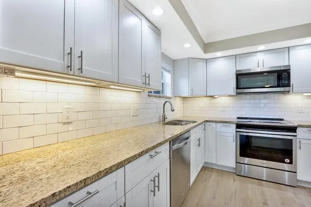 a kitchen with stainless steel appliances granite countertop a sink stove and microwave