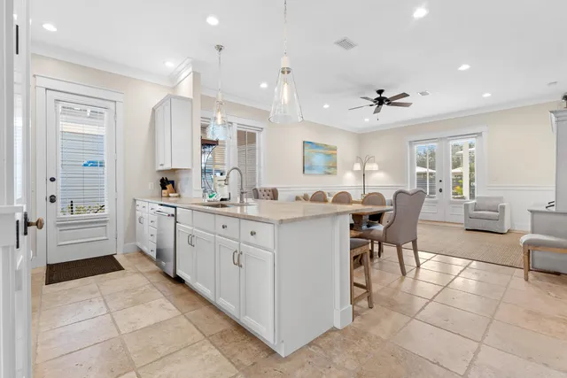 a kitchen with stainless steel appliances kitchen island granite countertop a dining table chairs and a refrigerator