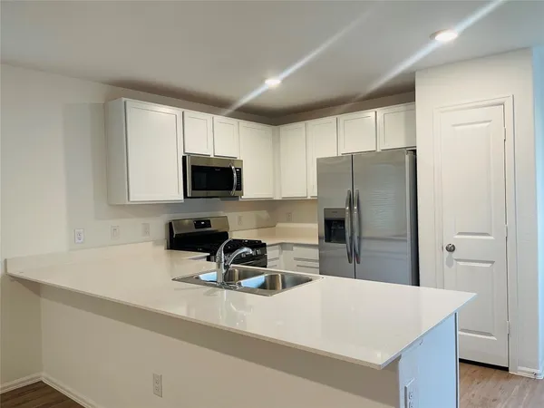 a kitchen with a refrigerator a microwave a sink and cabinets