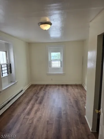 a view of an empty room with wooden floor and a ceiling fan