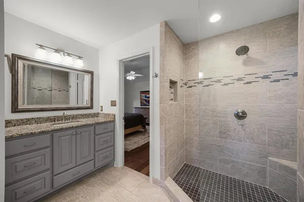 a bathroom with a granite countertop sink a mirror and a shower