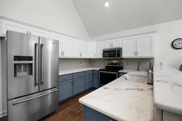 a kitchen with granite countertop a refrigerator stove and microwave