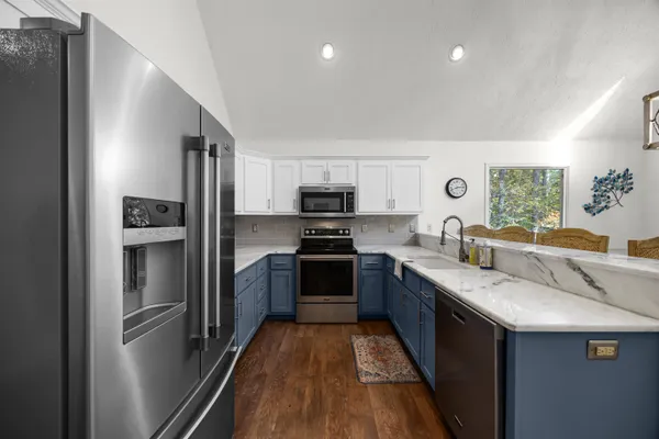 a kitchen with stainless steel appliances granite countertop a refrigerator a stove top oven a sink and dishwasher