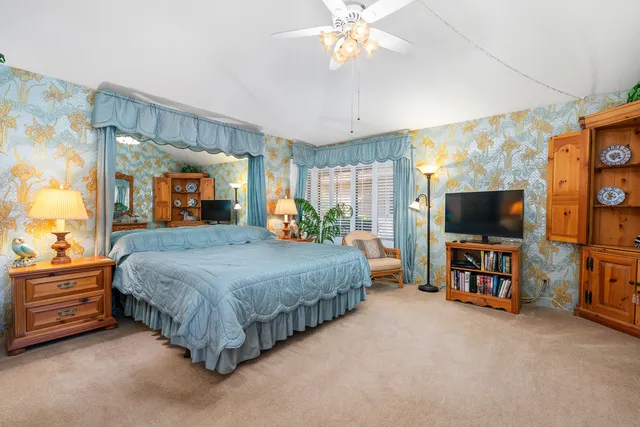 a spacious bedroom with a bed and a flat tv screen on dresser